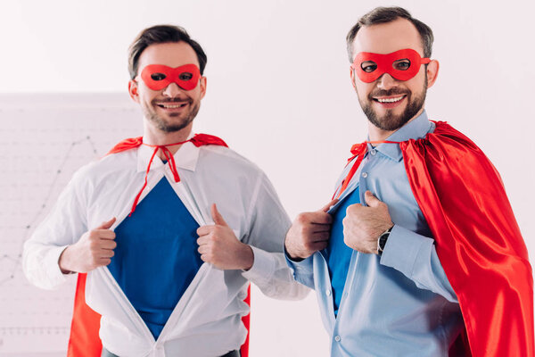 handsome super businessmen in masks and capes showing blue shirts in office