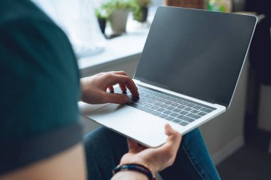 evde boş ekran ile dizüstü bilgisayar kullanan genç adam resmini kırpılmış