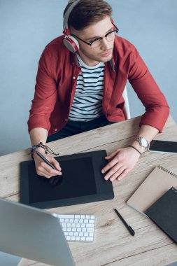 Adam freelancer iş bilgisayar ve grafik tablet içeren tablo tarafından Kulaklığımda