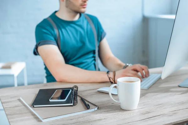 スマート フォン ノートブック 一杯のコーヒーの背後に働くフリーランサーのクローズ アップ ビュー — ストック写真