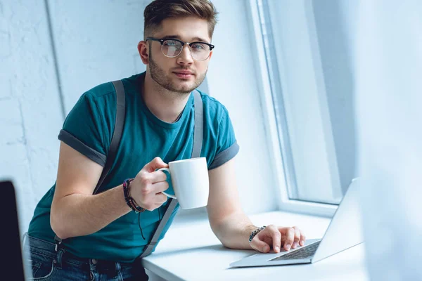 Jovem Óculos Segurando Xícara Café Olhando Para Câmera Enquanto Usa — Fotografia de Stock