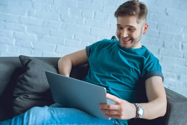 Smiling Young Man Using Laptop Sofa Home — Free Stock Photo