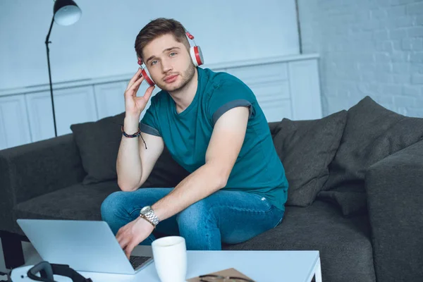 Schöner Junger Mann Mit Kopfhörer Schaut Die Kamera Während Hause — kostenloses Stockfoto