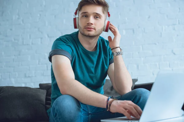 Giovane Uomo Cuffia Utilizzando Computer Portatile Guardando Fotocamera Casa — Foto stock gratuita