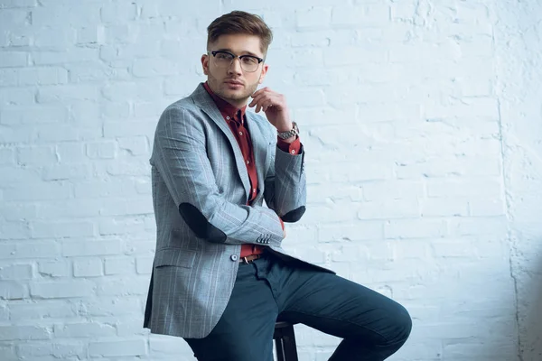 Joven Barbudo Vestido Con Traje Elegante Sentado Frente Pared Blanca —  Fotos de Stock