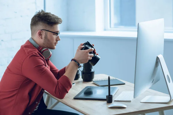 Jovem Segurando Câmera Sentado Mesa Com Computador Casa Escritório — Fotografia de Stock