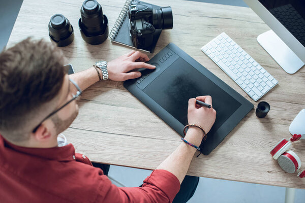 Freelancer man drawing with graphic tablet by table with computer
