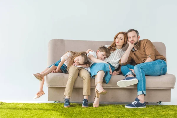 Família Com Duas Crianças Descansando Sofá Olhando Para Câmera Cinza — Fotografia de Stock