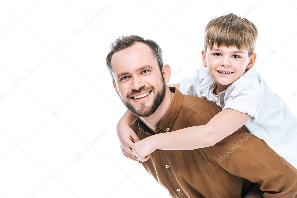 happy father piggybacking little son and smiling at camera isolated on white