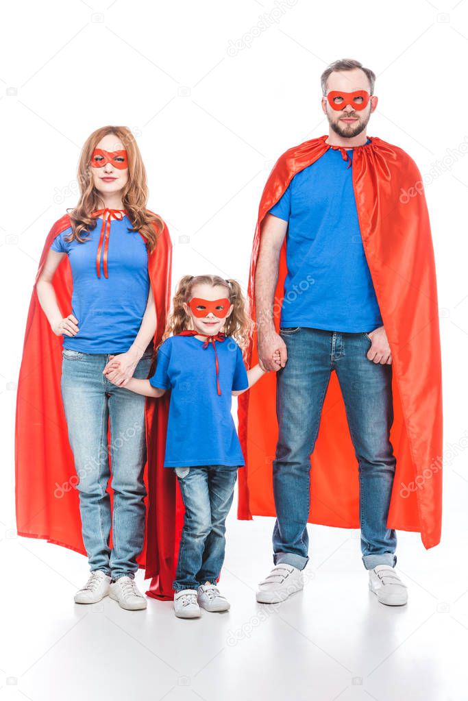 family of superheroes holding hands and looking at camera isolated on white