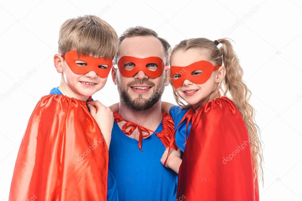 happy father and kids in superhero costumes smiling at camera isolated on white
