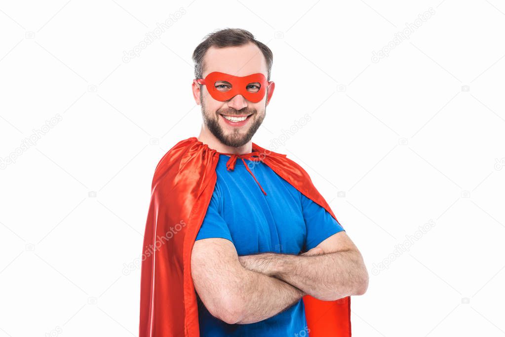 handsome bearded man in superhero costume standing with crossed arms and smiling at camera isolated on white