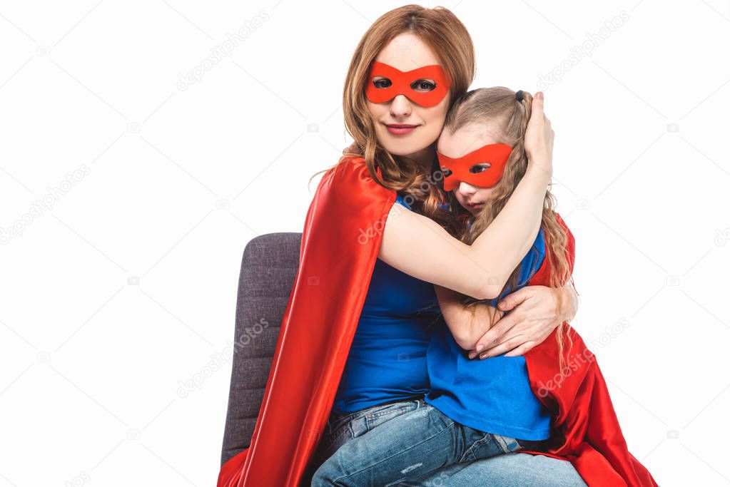 mother and daughter in masks and cloaks hugging isolated on white