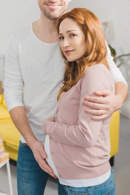 gülümseyen genç adam güzel hamile karısı evde sarılma kadeh kırpılmış