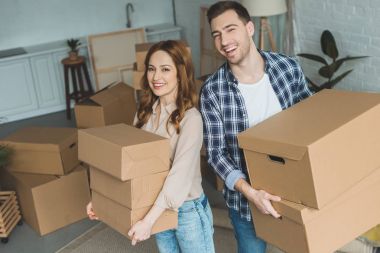 portrait of young couple with cardboard boxes at new home, moving house concept clipart