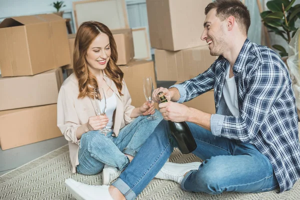 Glückliches Junges Paar Feiert Umzug Mit Champagner Während Neben Kartons — Stockfoto