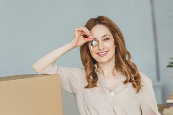 obscured view of smiling woman with keys from new apartment in hand, relocation concept