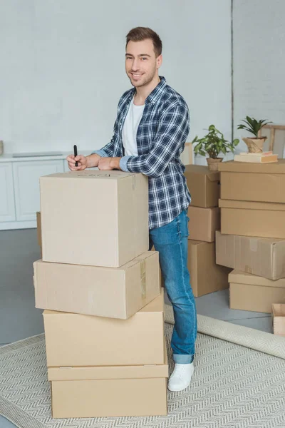 Smiling Man Signing Cardboard Box Moving Home Relocation Concept — Stock Photo, Image