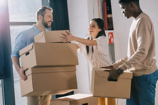 Compañeros Trabajo Multiétnicos Sonrientes Que Llevan Cajas Cartón Durante Reubicación —  Fotos de Stock