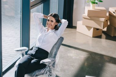 mutlu genç iş kadını elle baş ve yeni office kamerada gülümseyen arkasında oturan yüksek açılı görünüş