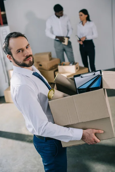 Businessman Holding Cardboard Box Office Supplies Looking Camera While Colleagues — Free Stock Photo