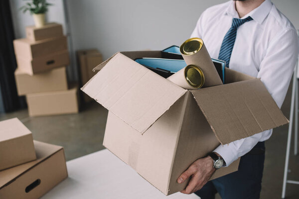 cropped shot of businessman holding cardboard box with office supplies