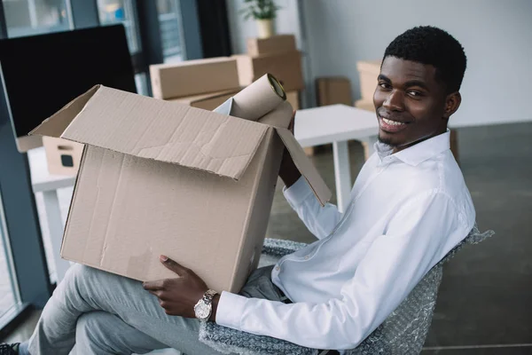 Hombre Negocios Afroamericano Feliz Sonriendo Cámara Mientras Sostiene Caja Cartón —  Fotos de Stock