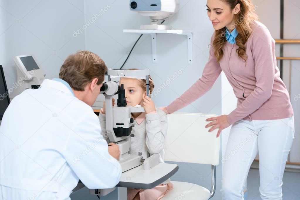 ophthalmologist examining child with slit lamp in consulting room