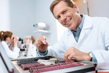 meslektaşım çocuk ile görme alanı test incelenmesi sırasında deneme çerçeve için objektifler tutan erkek gülümseyen göz doktoru