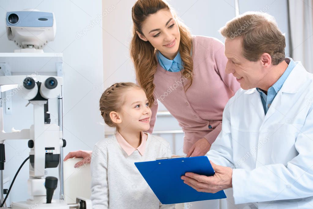 smiling ophthalmologist showing something to patient in clipboard