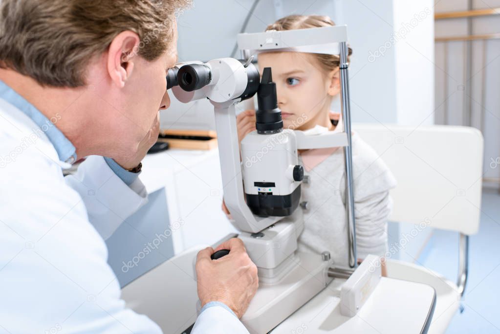 ophthalmologist examining vision of preteen kid with slit lamp in clinic