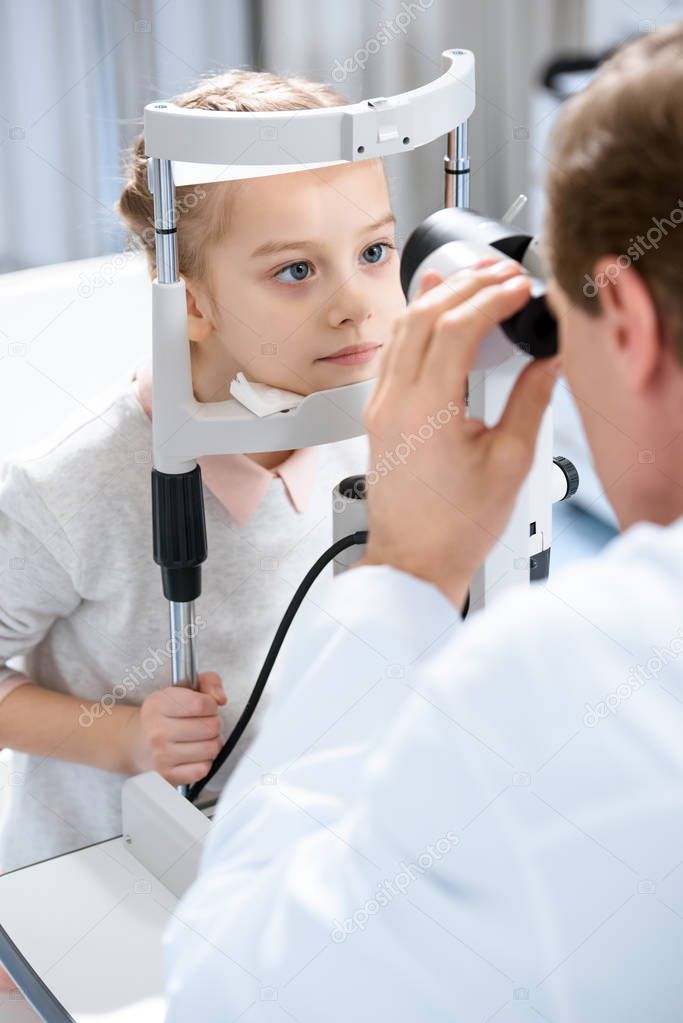 cropped image of ophthalmologist examining vision of child with slit lamp in clinic