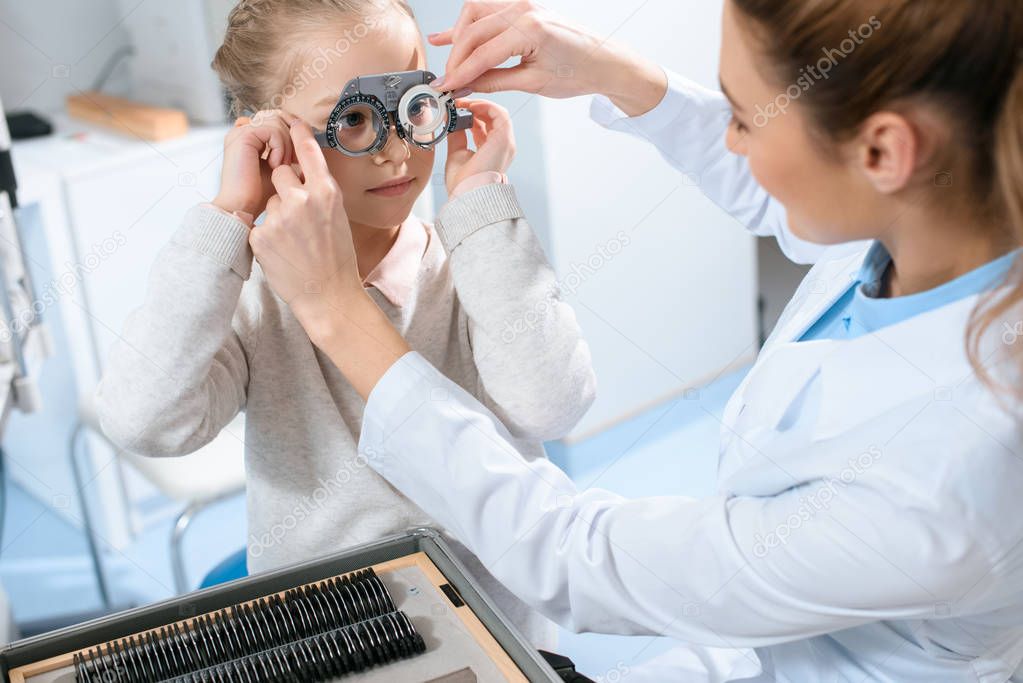 female ophthalmologist examining kid eyes with trial frame and lenses