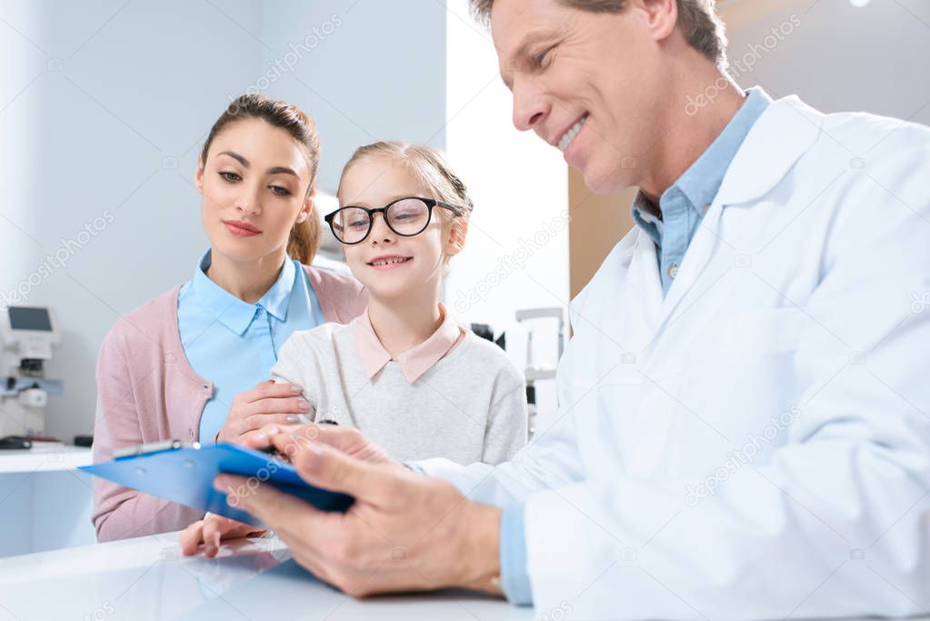 mother and daughter in glasses visiting oculist in clinic 