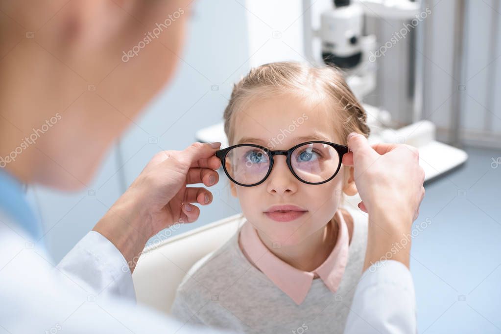 optometrist and little kid in glasses in optics 