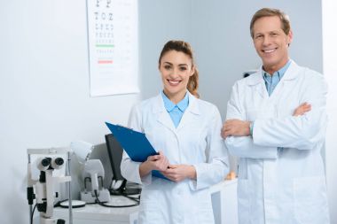 smiling ophthalmologists standing with diagnosis in clinic  clipart