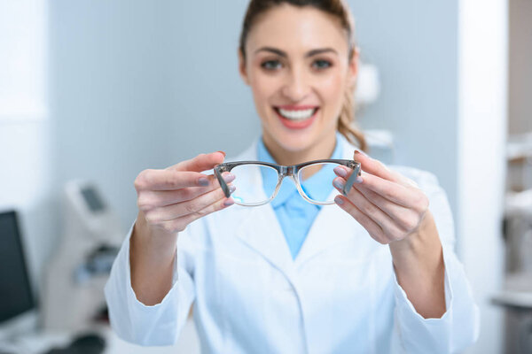 selective focus of female oculist holding eyeglasses