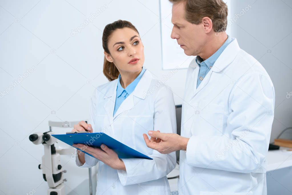 male and female ophthalmologists writing diagnosis in clinic