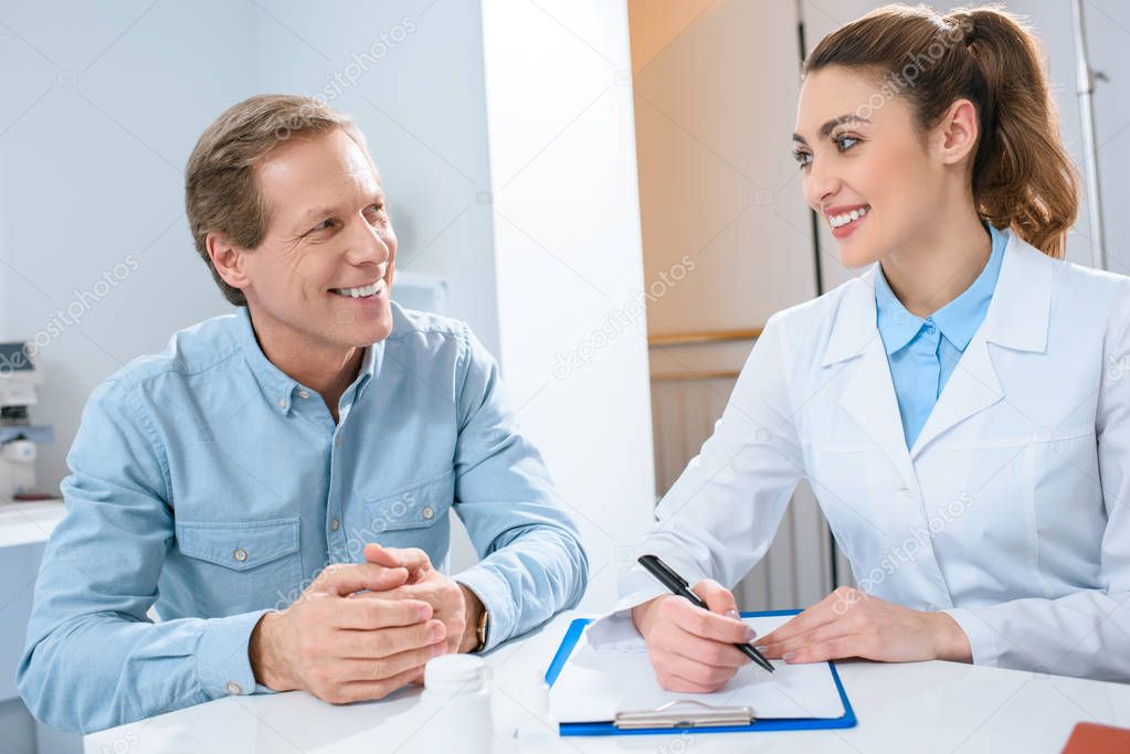 man having consultation with beautiful oculist writing diagnosis in clinic
