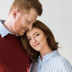 Portrait of beautiful happy redhead couple standing together isolated on grey