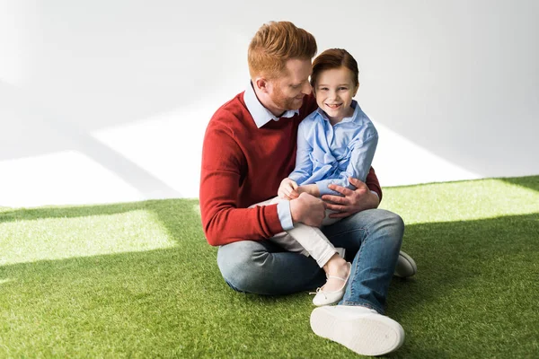 快乐的红头发的父亲和女儿坐在一起在草地上 — 图库照片