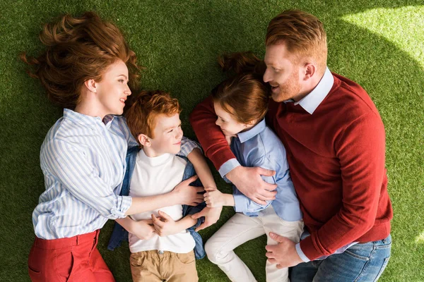 芝生の上には 一緒に横になっている 人の子供を持つ幸せな赤毛家族の平面図 — ストック写真