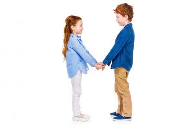 Elele ve birbirlerine beyaz izole gülümseyen şirin mutlu çocuklar yan görünüm