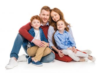 İki çocukla birlikte oturan ve üzerinde beyaz izole kamera gülümseyen güzel mutlu Kızıl aile 