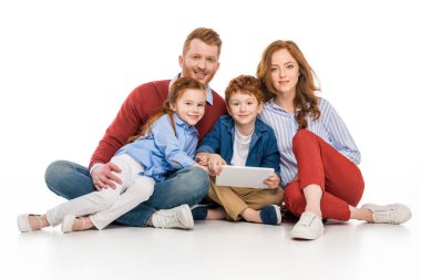 Dijital tablet kullanarak ve üzerinde beyaz izole kamera gülümseyen mutlu Kızıl saçlı aile