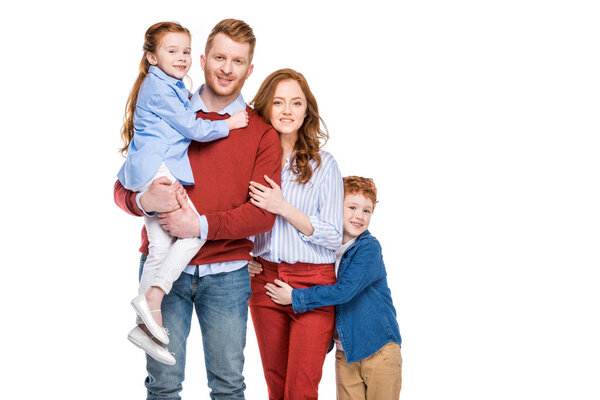 красивая счастливая рыжая семья с двумя детьми, улыбающаяся на камеру
