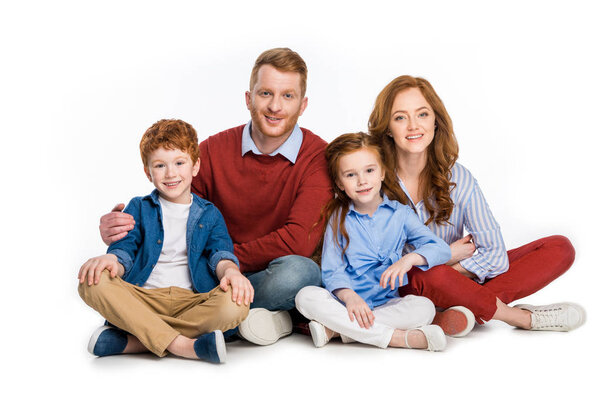 happy family with two kids sitting together and smiling at camera isolated on white