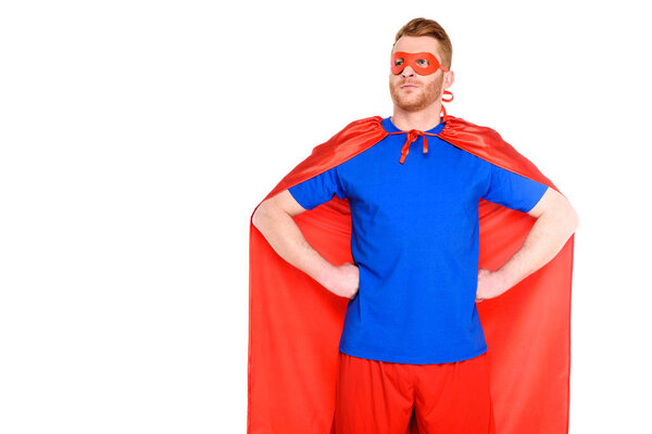 handsome man in superhero costume standing with hands on waist and looking away isolated on white