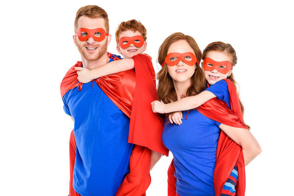super parents piggybacking happy kids in masks and cloaks isolated on white