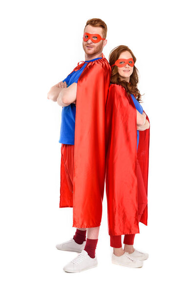 full length view of couple of superheroes in costumes standing with crossed arms and looking at camera isolated on white